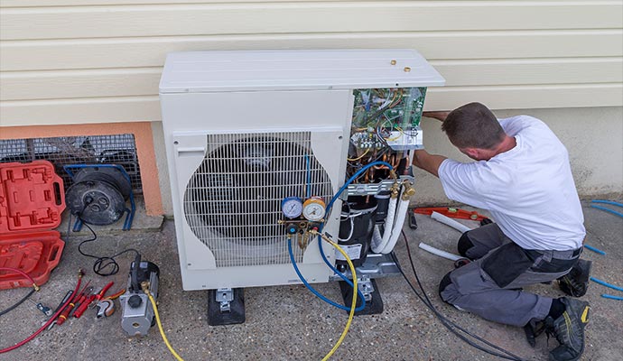 HVAC technician servicing outdoor heat pump with gauges HVAC technician servicing outdoor heat pump with gauges