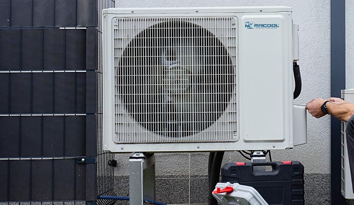 MrCool outdoor heat pump being installed beside a house