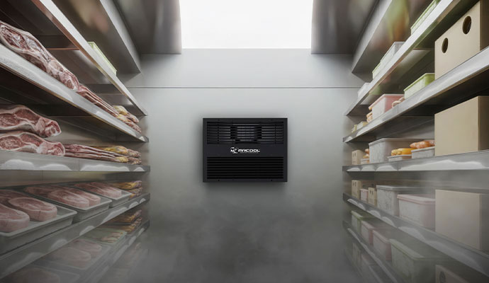 Wide view of a commercial cold storage facility with food products on shelving and a center MrCool refrigeration unit