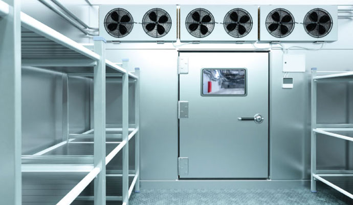 Industrial walk-in cooler entryway with heavy-duty door and overhead six-fan refrigeration cooling system