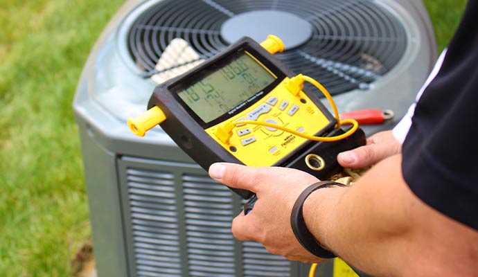 Technician diagnosing AC unit with digital manifold gauge
