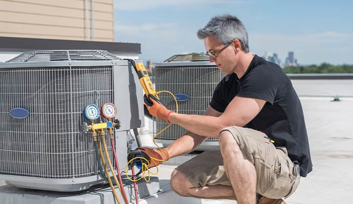 Technician with gauges reading the pressure of the refrigerant
