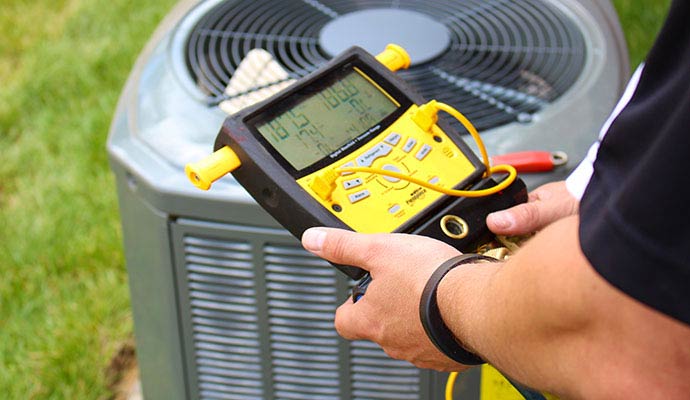 Technician testing AC unit with digital manifold gauge