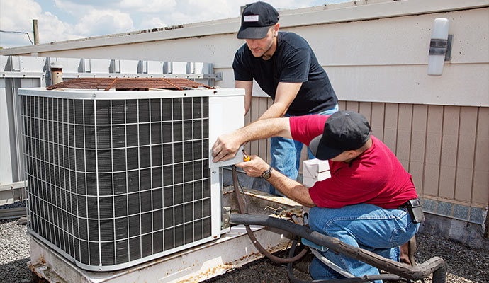 Technicians repairing an outdoor AC